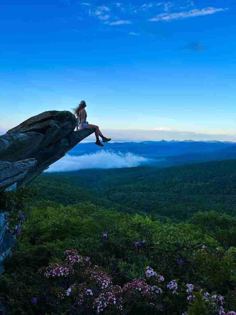 woman sits on a ledge overlooking wildflowers in Boone, North Carolina
