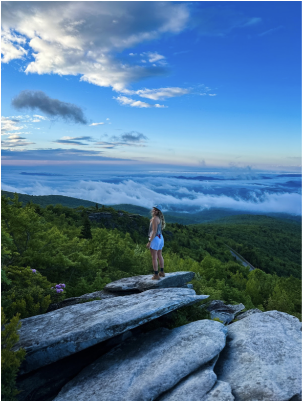 girl standing on a rock overlooking a cloud aversion 