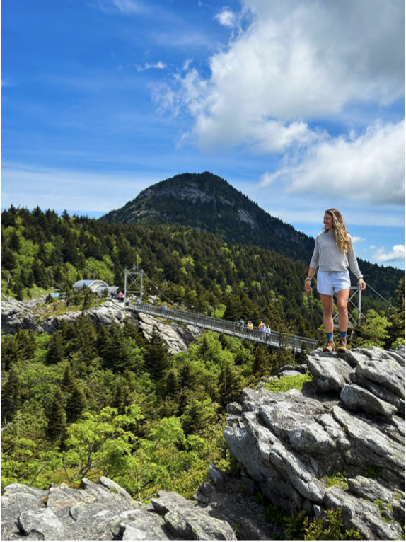 girl stands on a rock overlooking the Mile High Swinging Bridge in North Carolina