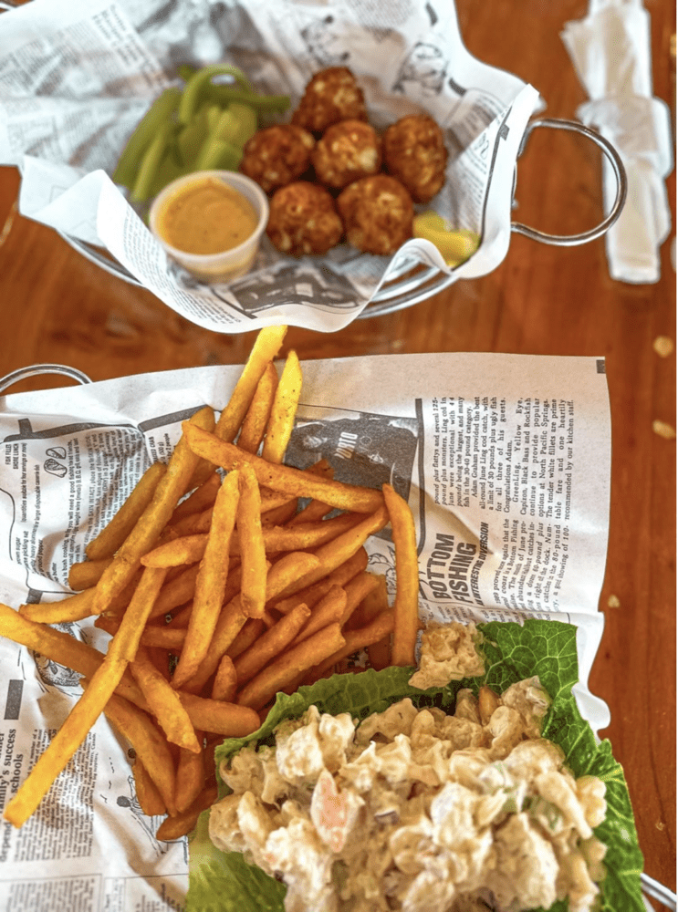 a flat lay of French fries and fish salad with hushpuppies