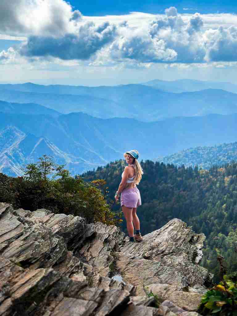 hiker stands on a cliff side over looking rolling mountains of Great Smoky Mountain National Parks